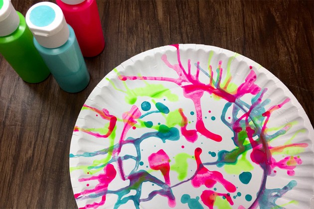 A painted paper plate and bottles of paint.