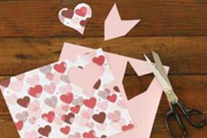 Cutting heart and feather shapes from paper.