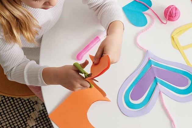 A child at a table cutting out heart shapes. 