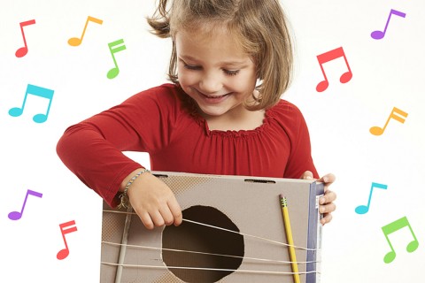 A child playing a guitar made from a box and rubber bands.